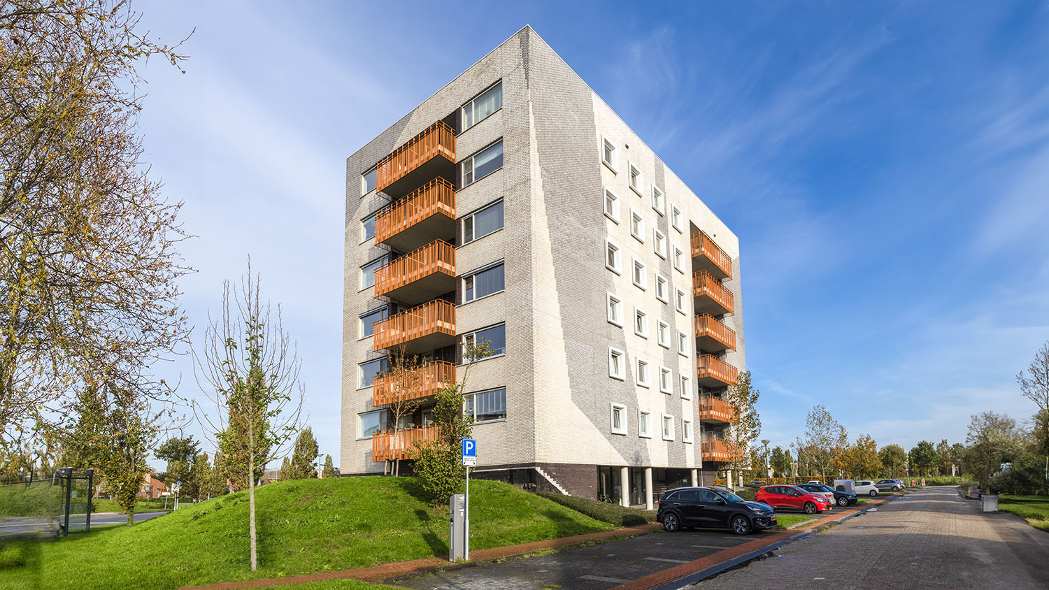 Een wit appartementencomplex met oranje balkons